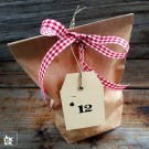 24 Papiertüten, in unterschiedlicher Höhe zu befüllen. Jeweils mit Nummer und 0,75 m kariertem Schleifenband aus Stoff.